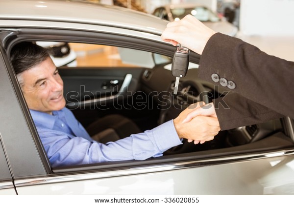 Customer receiving car keys while shaking hand in\
a garage