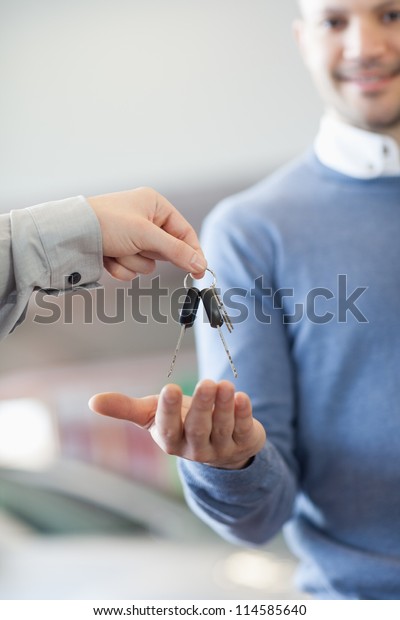 Customer\
receiving keys from a car dealer in a car\
shop