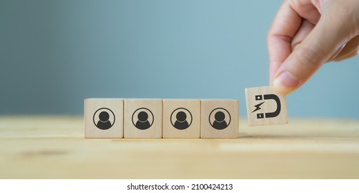 Customer retention concept. Inbound marketing strategy. Attracting potential customers.  Hand puts wooden cubes with magnet attracts customer icons on beautiful grey background and copy space. Loyalty