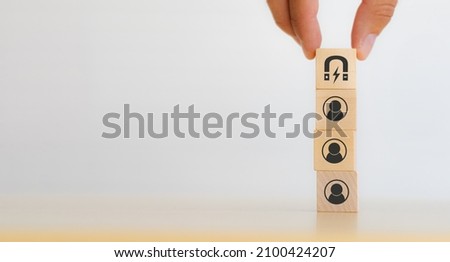 Customer retention concept. Inbound marketing strategy. Attracting potential customers.  Hand puts wooden cubes with magnet attracts customer icons on beautiful white background and copy space.