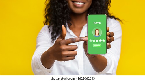 Customer Review Concept. Unrecognizable Black Woman Pointing At Smartphone With Rating Application On Screen, Yellow Studio Background, Panorama