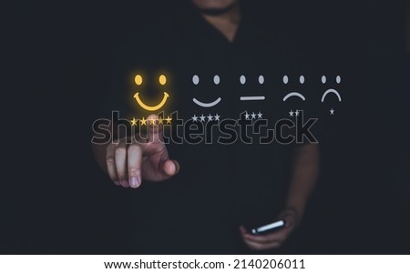 Customer review good rating concept hand pressing smile face icon and five star on visual screen for positive customer feedback, testimonial and testimony.