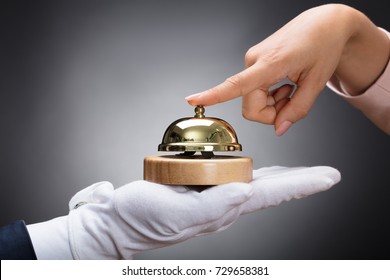Customer Ringing Service Bell Held By Customer In Front Of Grey Background