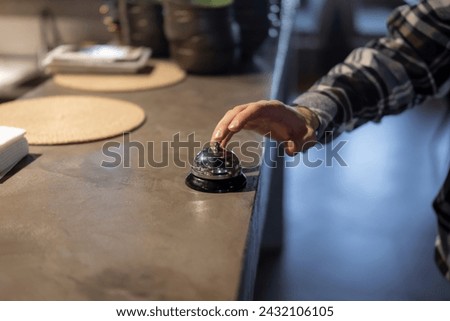 Customer Rings Service Bell at Counter in Casual Restaurant During Evening Hours