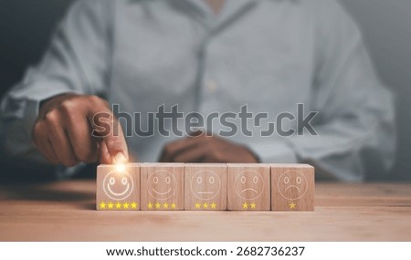Customer satisfaction concept. Client hand selecting five-star smiley face on wooden block. Representing excellent service rating, positive experience and quality feedback in business evaluation.