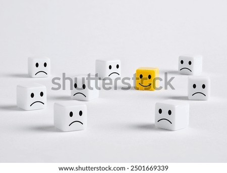 Customer satisfaction or user experience concept. Single yellow cube with a smiling face is standing out in a crowd of unhappy white cubes.