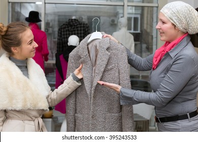 Customer Selecting Jacket At Clothing Department Store Talking With Saleslady Who Explains Features And Trying To Convince To Make Purchase Shop Interior With Many Items And Windows On Background