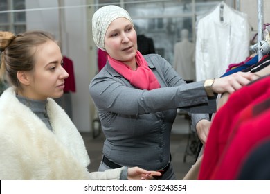 Customer Selecting Jacket At Clothing Department Store Talking With Saleslady Who Explains Features And Trying To Convince To Make Purchase Shop Interior With Many Items And Windows On Background