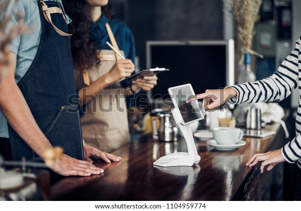 customer self\
service order drink menu with tablet screen at cafe counter\
bar,seller coffee shop accept payment by mobile.digital lifestyle\
concept.Blank space for display of\
design