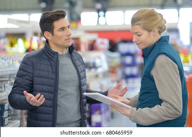 Customer And Seller Choosing Hammer In Household Store