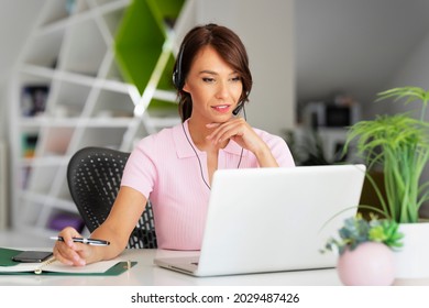 Customer service assistant wearing headset while sitting behind her laptop and working in the call center.  - Powered by Shutterstock