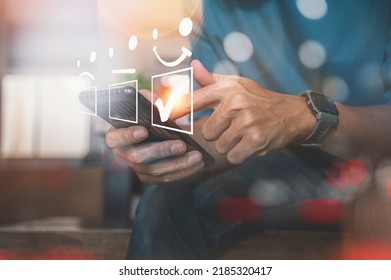 Customer service evaluation concept. Asian man is using smartphone and pressing face emoticon smile in satisfaction on virtual touch screen. - Shutterstock ID 2185320417