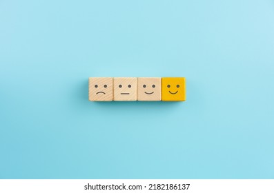Customer service evaluation and satisfaction survey concepts, evaluation, Increase rating. Happy face smile face icon on wooden cube on blue background - Shutterstock ID 2182186137