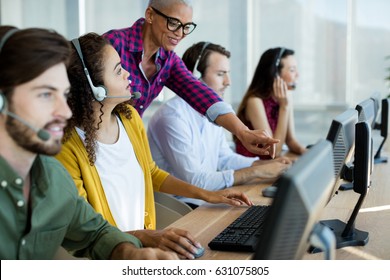 Customer service executive trainer assisting her team at office - Powered by Shutterstock