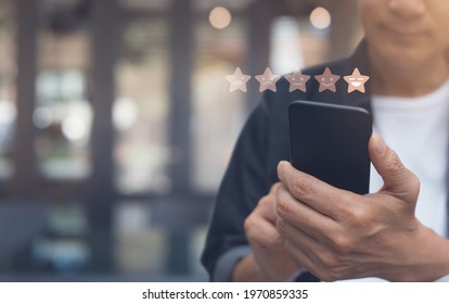 Customer Service Experience And Business Satisfaction Survey. Man Hand Using Mobile Phone With Icon Five Star Symbol To Increase Rating Of Company Concept