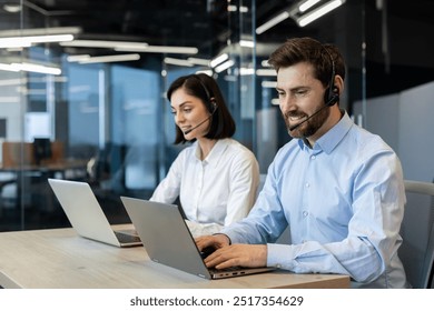 Customer service representatives engaged in professional work using headsets and laptops. Team collaboration and effective communication emphasized in a modern office environment - Powered by Shutterstock