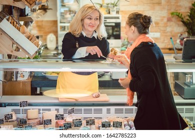 Customer and shop clerk at the cheese counter of supermarket testing cheese