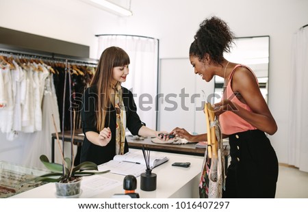 Customer shopping designer wear at a fashion boutique. Customer making payment by entering her pin in point of sale machine.