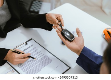 A customer signs a rental agreement for a new car at a dealership. The salesman explains the finance options and insurance details. With the paperwork complete, the keys are handed over, sealing the d - Powered by Shutterstock