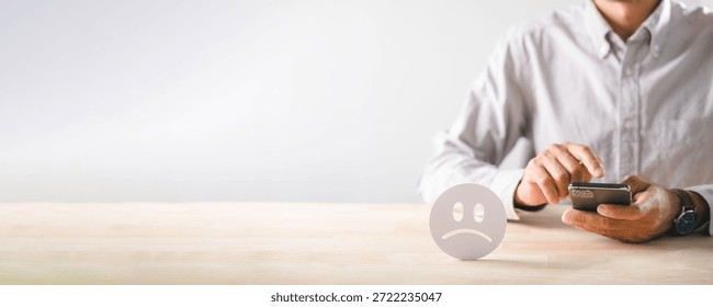 Customer submits negative feedback, expressing unhappiness bad experience, giving low satisfaction rating via mobile phone, sad face icon shows poor service review.