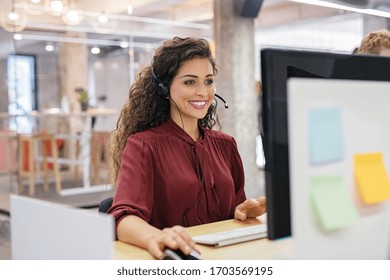 Customer support phone operator working at computer. Happy call center agent working on support hotline in office. Smiling call center agent in conversation with customer over headset.  - Shutterstock ID 1703569195