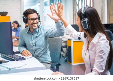 Customer support representative operators giving high five to each other celebrating successful task done at office. - Powered by Shutterstock