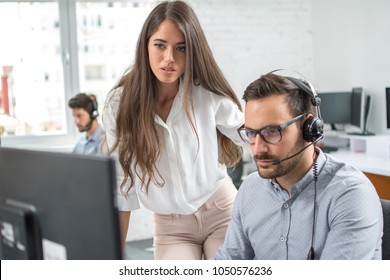 Customer support workers solving problems together on client's online account in call centre office.