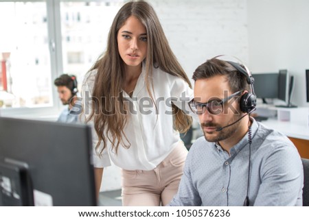 Customer support workers solving problems together on client's online account in call centre office.