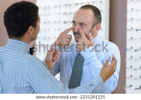 customer talking to optician and pointing to his nose