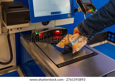 Customer uses scanner for bread purchase. Retail customer scans bread using electronic checkout technology. Modern shopping experience with automated scanning and digital payment systems