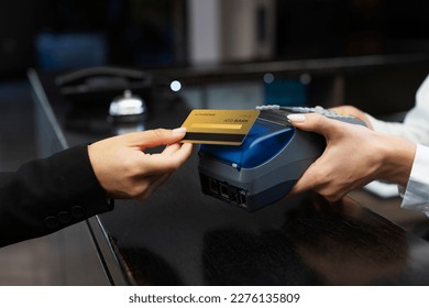 Customer using credit card for payment to receptionist. cashless technology and credit card payment concept. customer paying with contactless credit card. NFC technology. credit card reader machine.