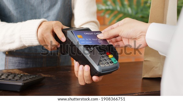 Customer using\
credit card for payment to owner at cafe restaurant, cashless\
technology and credit card payment\
concept