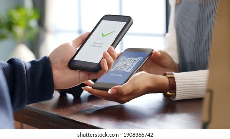 Customer using phone for payment at cafe restaurant, cashless QR code technology and money transfer concept - Shutterstock ID 1908366742