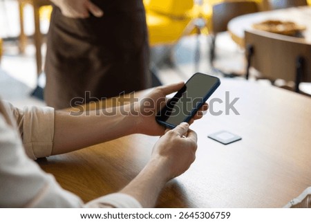 Customer using phone to scan menu at restaurant