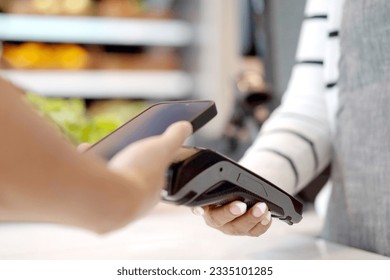 Customer using wireless digital payment on smartphone and credit card at the supermarket or grocery store. 