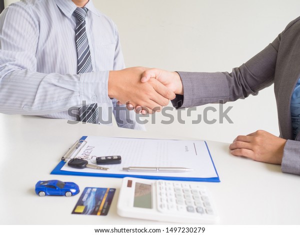 Customer woman used credit card and\
signed for rent car form salesman, Shake hands deal\
business.