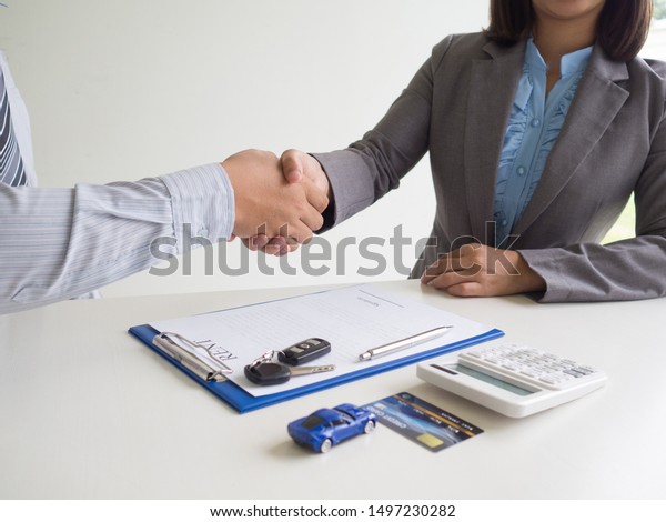 Customer woman used credit card and\
signed for rent car form salesman, Shake hands deal\
business.