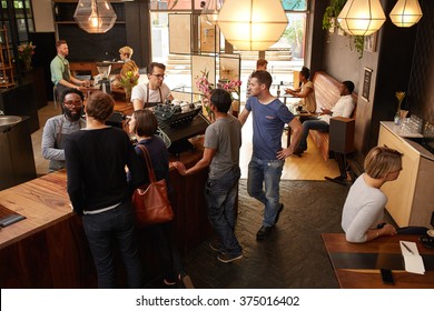 Customers At The Counter Of Cafe Being Helped By Barista