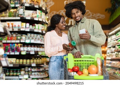 Customers Couple Choosing Products Using Phone During Grocery Shopping In Modern Supermarket Indoor. Happy Buyers Browsing Internet On Smartphone Buying Food In-Store - Powered by Shutterstock