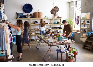 Customers and staff in a busy clothes shop - Shutterstock ID 558968941