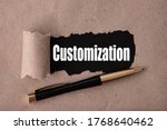 CUSTOMIZATION text written under torn paper and a recumbent metal pen. Business strategy concepts.