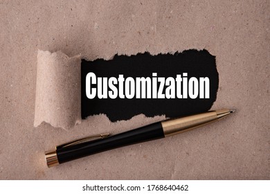 CUSTOMIZATION text written under torn paper and a recumbent metal pen. Business strategy concepts.