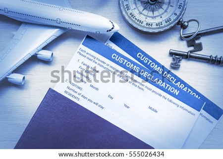 Customs declaration form on a wood table with a white model airplane. The purpose of the form is to declare what goods are been brought into the nation, as some may have limits or customs excise tax.
