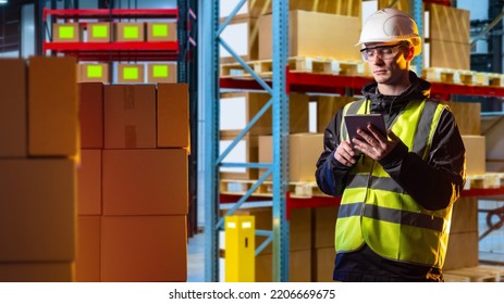 Customs Officer. Man Customs Officer In Warehouse Building. Warehouse Worker. Guy With Tablet Checks Customs Declaration. Cardboard Boxes In Front Of Man. Blurred Boxes On Racks In Background