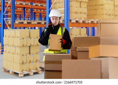 Customs registration. Woman with phone in warehouse. Woman works at customs. Warehouse specialist speaks on phone. Passage of goods across border. Customs officer at warehouse. Girl in white helmet - Shutterstock ID 2166971703