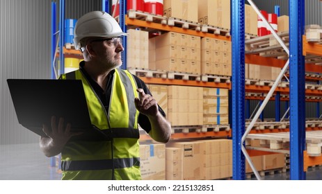 Customs Warehouse Worker. Man With Laptop Works At Customs. Guy With Computer Among Shelves. Racks With Boxes And Barrels. Man Wear Warehouse Worker Uniforms. Customs Officer. Selective Focus.