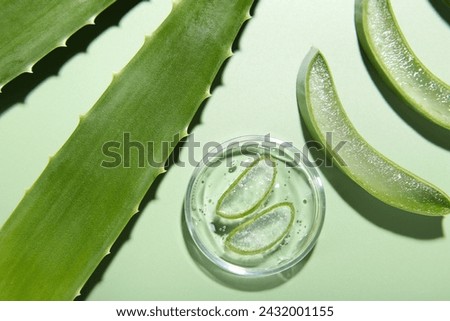 Cut aloe vera leaves and cosmetic gel on light green background, flat lay