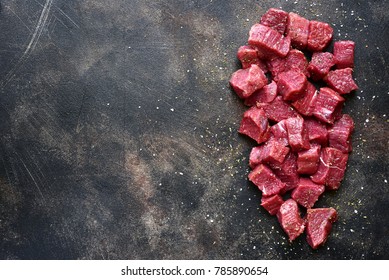 Cut beef with sea salt and dried herb on a dark metal or slate background.Top view with copy space.
