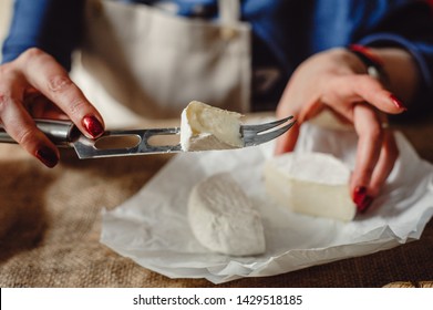 Cut Camembert cheese, French soft cheese with white mold in the hands of a woman on the background of a craft textile tablecloth, close-up. Knife for slicing cheese - Powered by Shutterstock