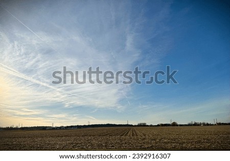 Cut Corn Field with Jetstreams and Cloudy Sky